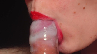 Oral sex in a condom very close up. Red lips caress and blow the cock.