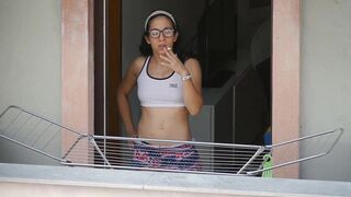 Brunette neighbor with glasses while smoking on the balcony